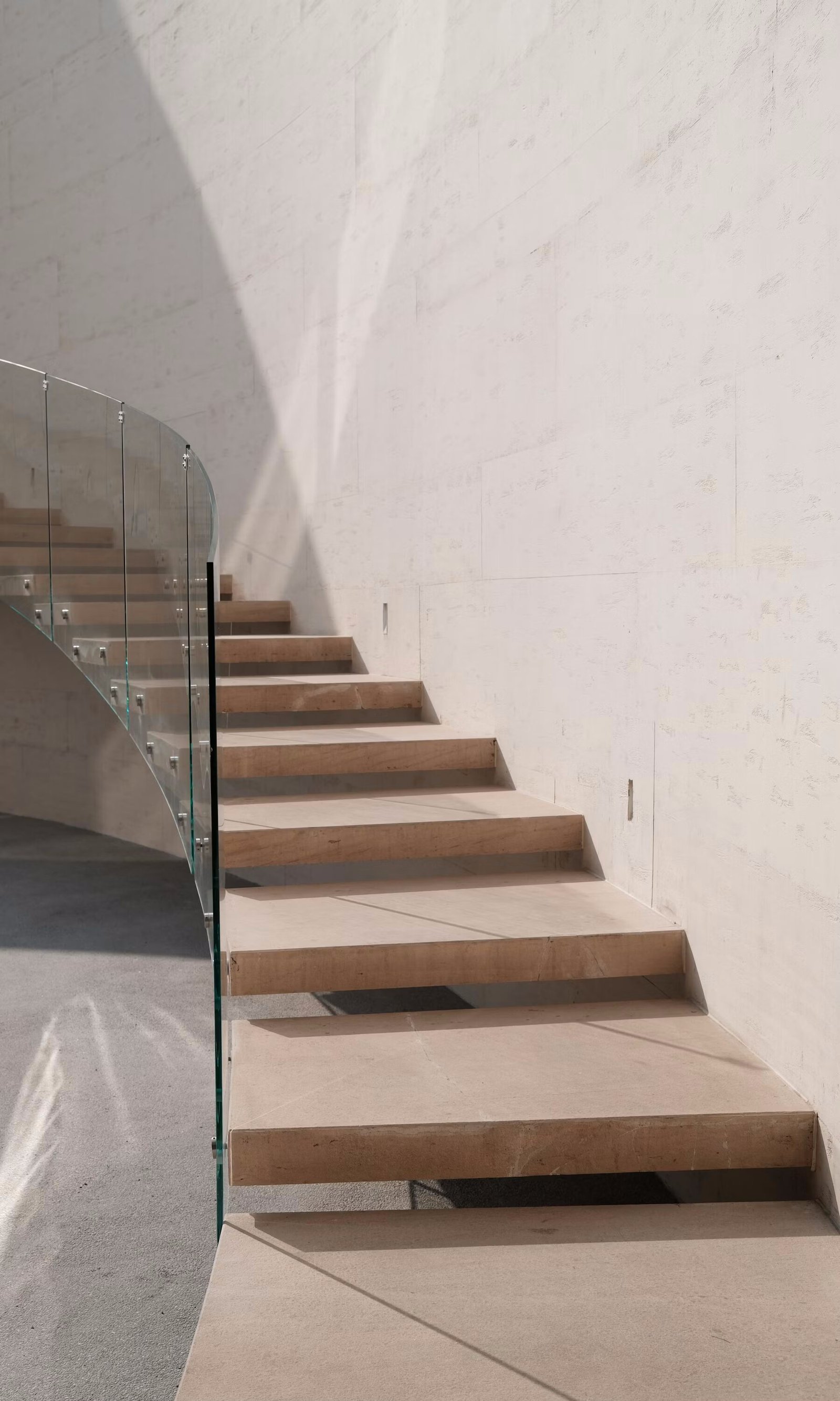 Elegant modern staircase with glass railing and marble wall
